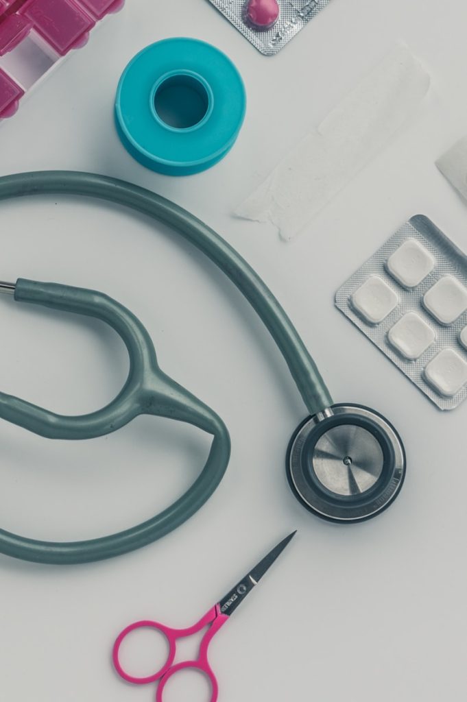 person sitting while using laptop computer and green stethoscope near